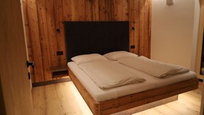 Ein Bett mit Holzkopf, Holzboden und weiße Wand.