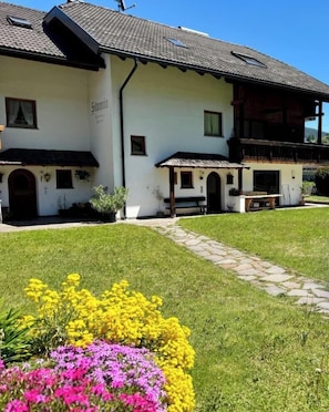 Un bâtiment traditionnel doté d’un toit en pente, d’un petit porche et d’un chemin menant à l’entrée.