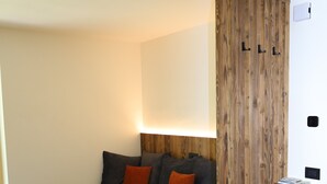 Ein modernes Schlafzimmer mit Schlafsofa, Holzschrank und Wandleuchte.