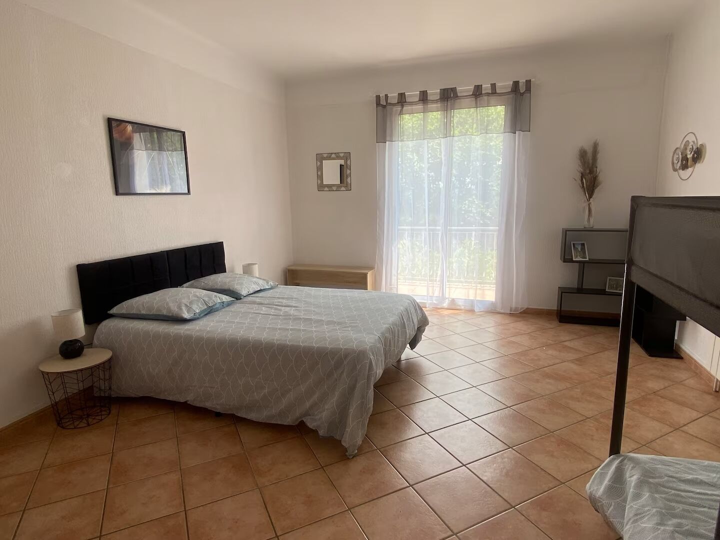 A bedroom with a bed, bedside tables, a TV, and a window with curtains.