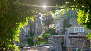 Un cortile con edifici in pietra, posti a sedere all'aperto e vegetazione.