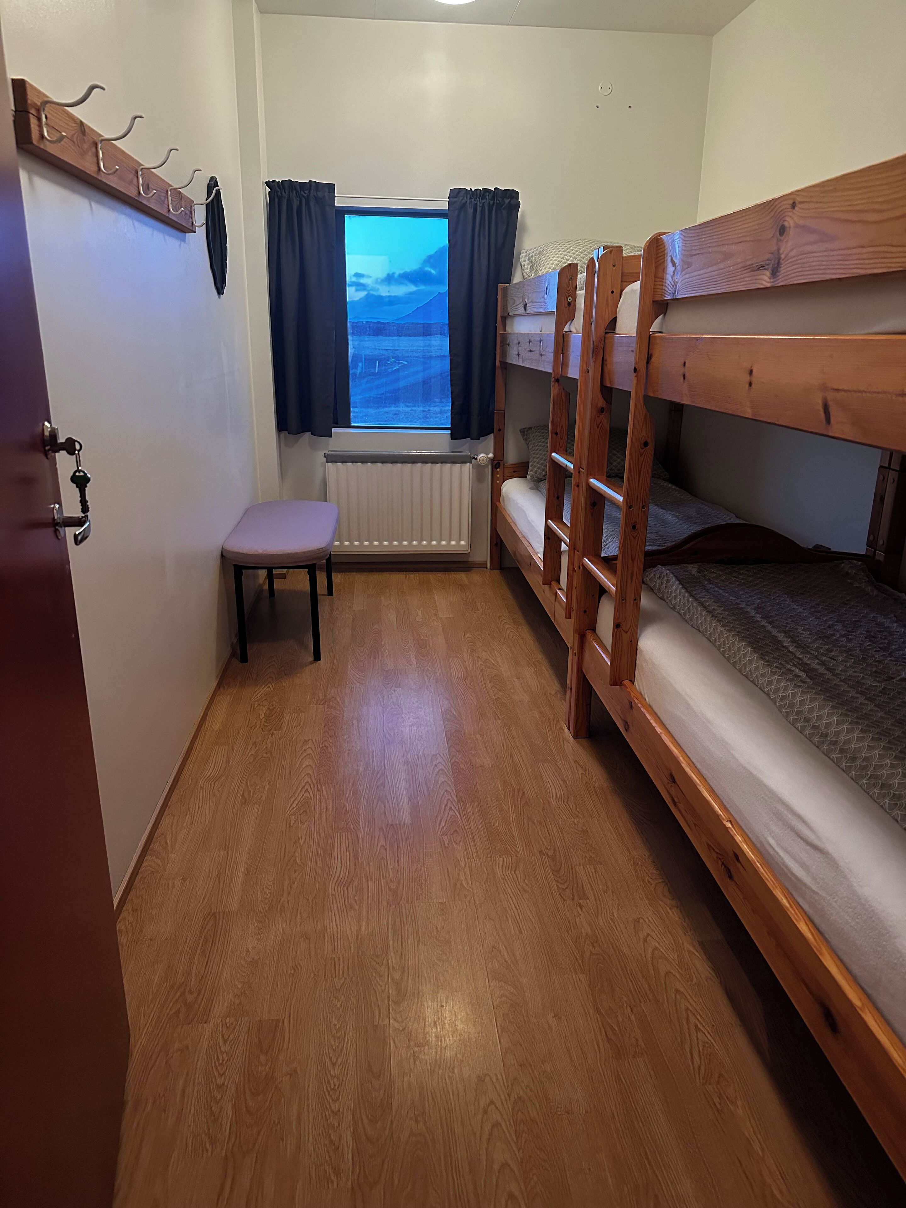A compact room with a bunk bed, a small table, and a window with curtains.