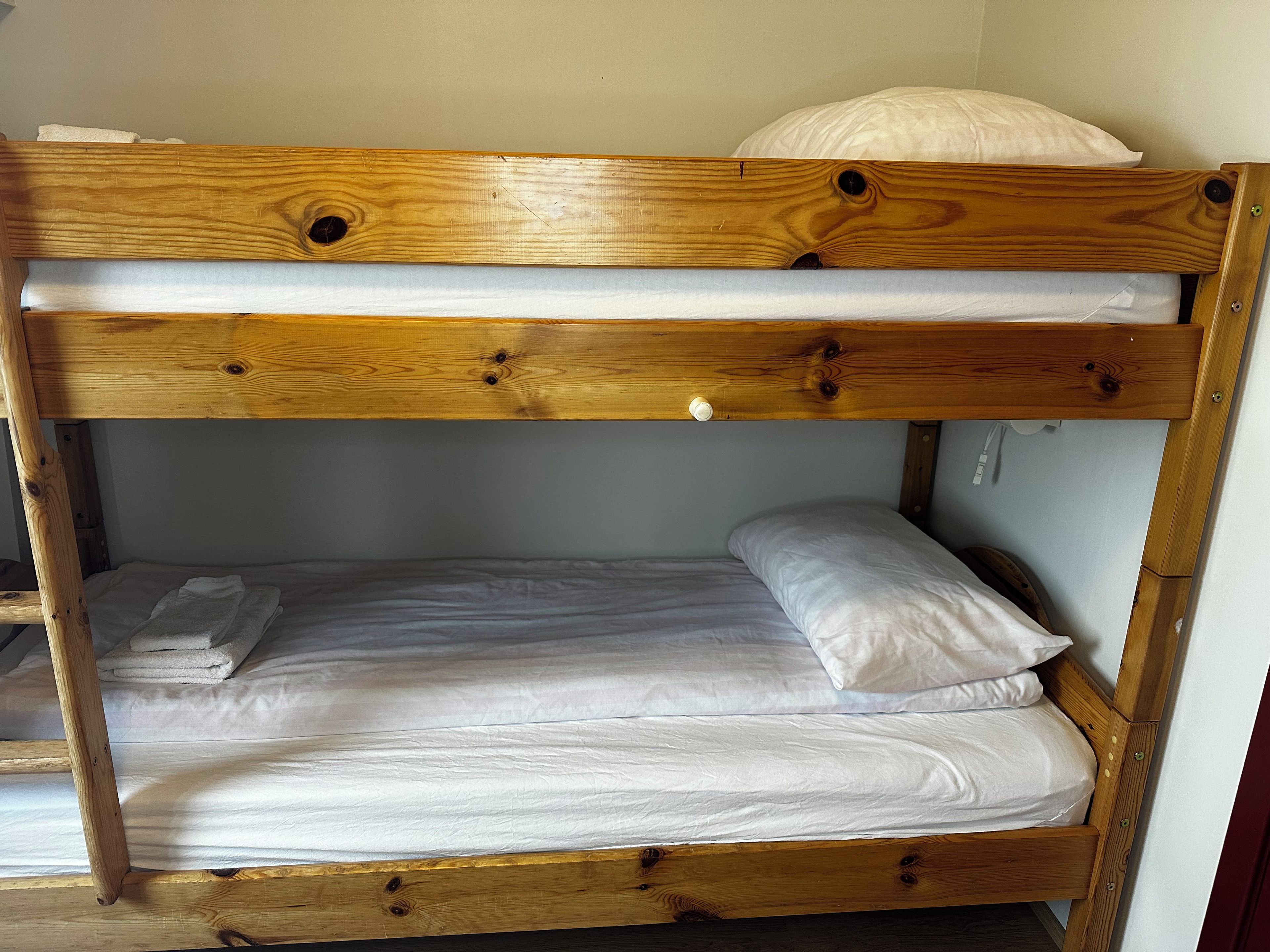 A bunk bed with a wooden frame and white bedding.