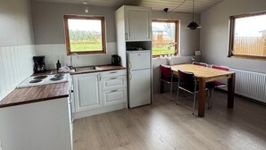 Una cocina compacta con armarios blancos, encimera de madera, una mesa de comedor con sillas y una ventana que ofrece vistas al exterior.