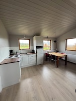 Una cocina compacta con armarios blancos, encimera de madera, una mesa de comedor con sillas y una ventana que ofrece vistas al exterior.
