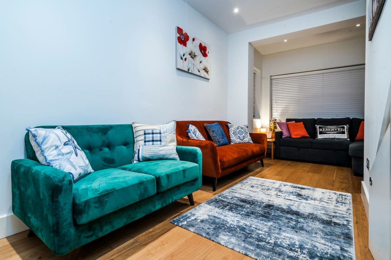 Ein modernes Wohnzimmer mit zwei Sofas, einem Teppich und einem Gemälde an der Wand.