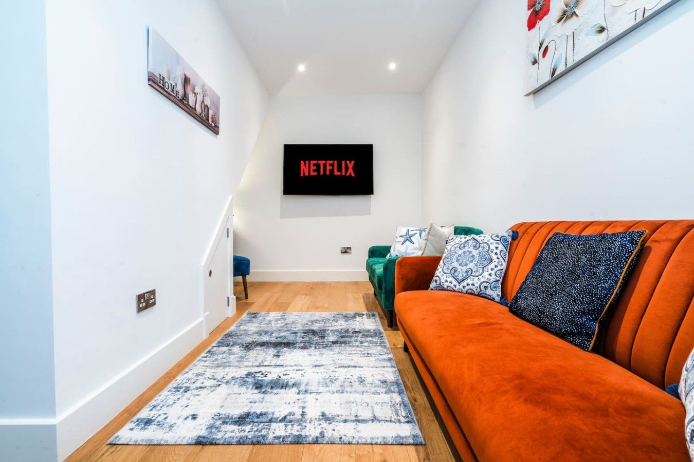 A modern living room with a sofa, a coffee table, and a flat-screen TV displaying 'NETFLIX'.