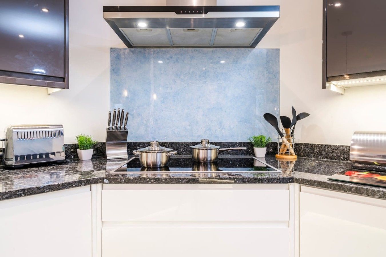 A modern kitchen with a built-in stove, a toaster, and a knife block.