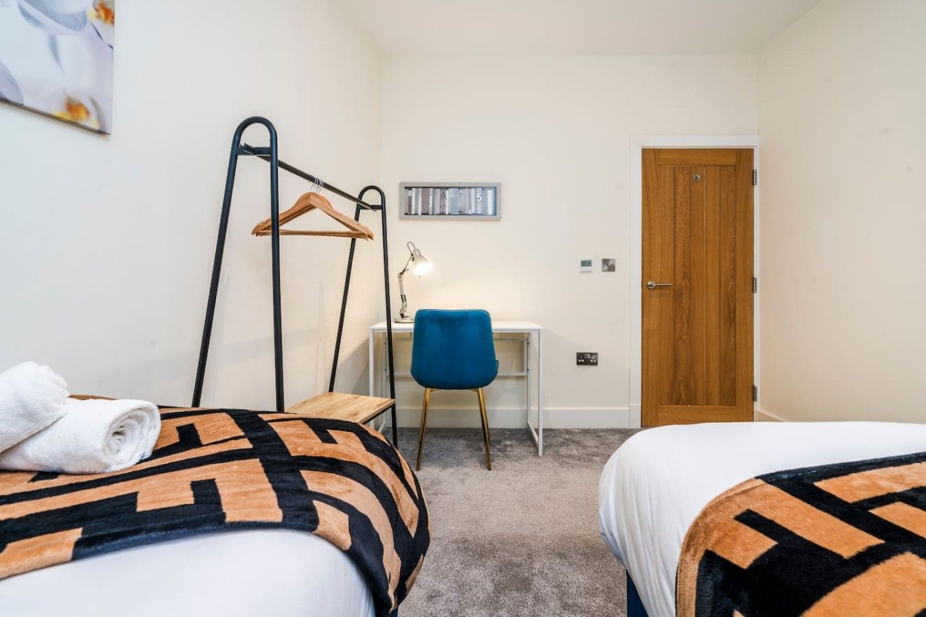 A hotel room with two beds, a desk, a chair, and a wardrobe.