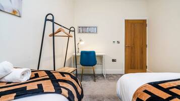 A hotel room with two beds, a desk, a chair, and a wardrobe.