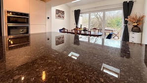 A modern kitchen with a large island, built-in ovens, and pendant lighting. - CosyRiverside House: Contractors, tourists free parking (Hemel Hempstead)