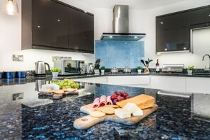 A modern kitchen with a central island, stainless steel appliances, and a blue backsplash.