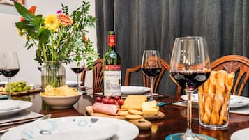 Ett matbord dukat med tallrikar, glas, en flaska Bordeauxvin, en vas med blommor och olika sorters mat.