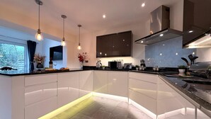 A modern kitchen with a central island, pendant lighting, and a view of the outdoors. - CosyRiverside House: Contractors, tourists free parking (Hemel Hempstead)