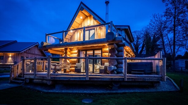 A log cabin with a wooden deck, large windows, and a chimney. - The Lookout (Ilkley)