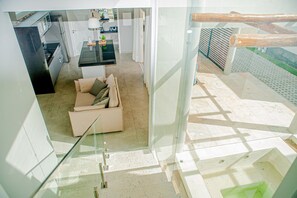 Una cocina moderna con refrigerador, estufa y pileta. En el área de estar, hay un sofá con almohadones.