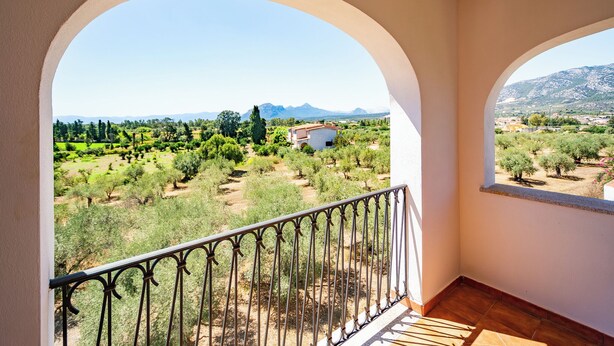A balcony with a wrought iron railing overlooking a rural landscape with trees and a building. - Bright Accommodation in Orosei (Orosei)