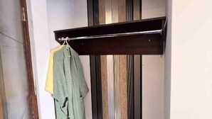 Una habitación con un banco de madera, un perchero con ropa y una pared a rayas.