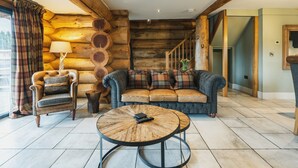 A log cabin interior with a leather armchair, a sofa, and a round coffee table. - Keepers Cabin (Ilkley)