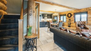 A log cabin interior with a staircase, a dining area, and a living room with a sofa and a chair. - Keepers Cabin (Ilkley)