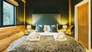 A cozy bedroom with a large bed, wooden headboard, and a fluffy rug. - Bears Den (Ilkley)