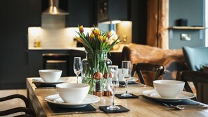A dining table set with white bowls, wine glasses, and a vase with flowers. - Bears Den (Ilkley)