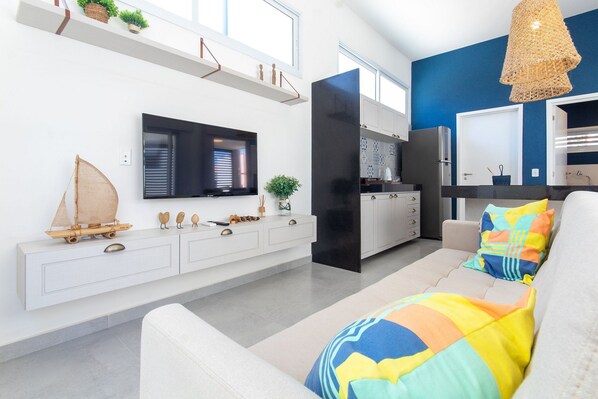 Ein modernes Wohnzimmer mit Sofa, Fernseher und Küchenbereich.