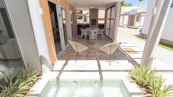 Un patio al aire libre con un jacuzzi, una mesa de comedor y sillas.