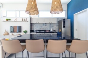 A modern kitchen with a central island, pendant lights, and a large window.