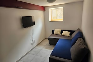 A small room with a bed, a TV mounted on the wall, and a window with a view.