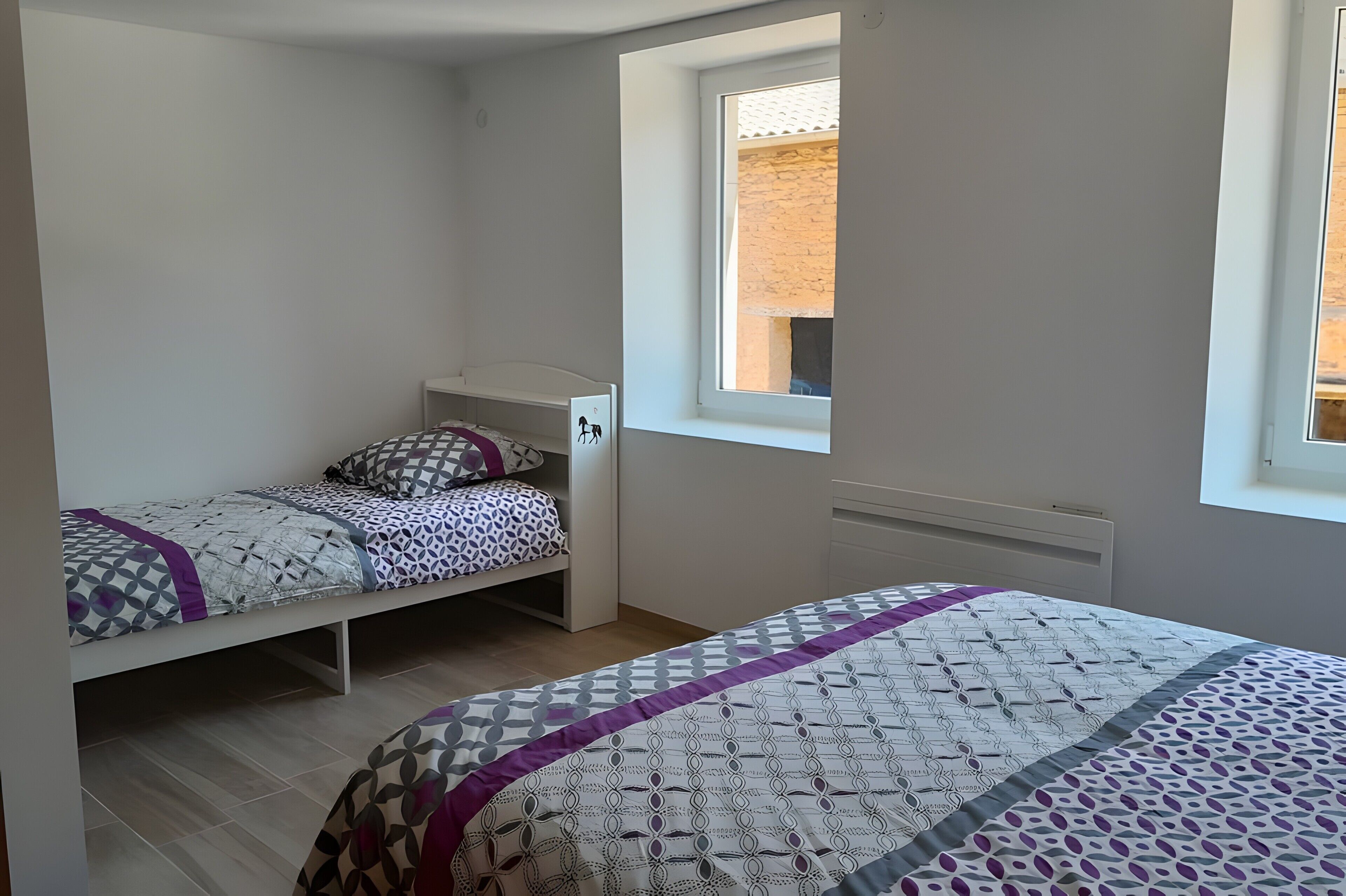 A bedroom with a bed, a window, and a radiator.