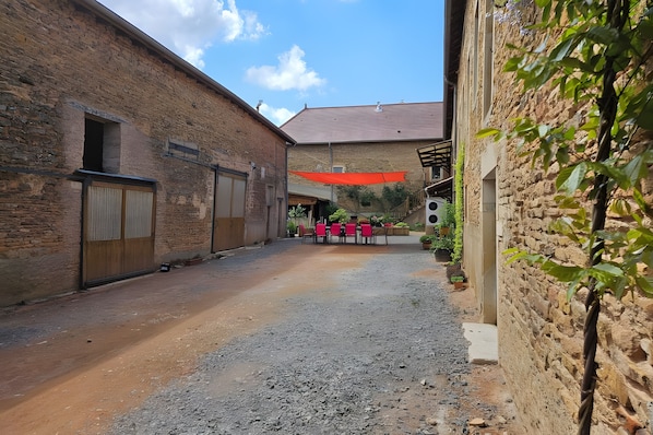 A courtyard with a gravel path, brick buildings, and a red canopy.