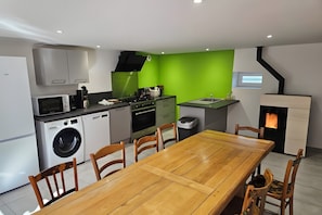 A modern kitchen with a dining area, a washing machine, a stove, and a small window.
