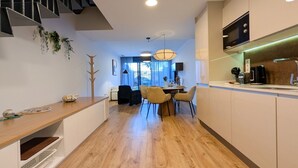 Eine moderne Küche mit Essbereich, Holzboden und einer Treppe.
