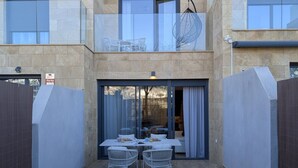 Eine moderne Außenpatio mit Tisch und Stühlen, eine Glastür, die auf einen Balkon führt, und Blick auf die Umgebung.