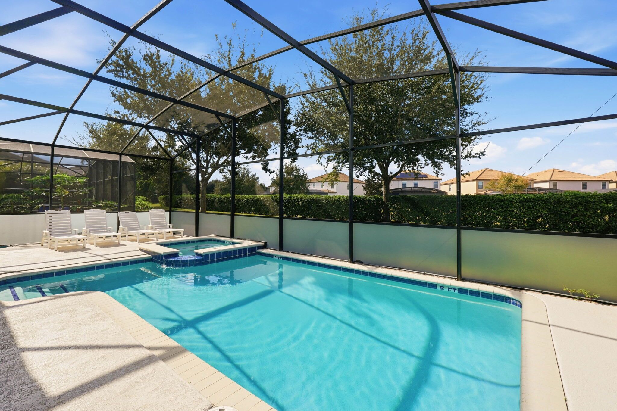 Une piscine dotée d’une structure en verre, entourée de chaises longues et offrant une vue sur des immeubles d’habitation.