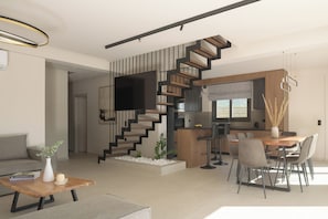 A modern living room with a wooden coffee table, a sofa, and a dining area with a wooden table and chairs. There is a staircase with a unique design leading to an upper level.