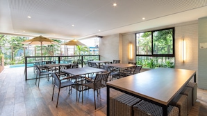 Un espace de restauration intérieur avec des tables et des chaises, de grandes fenêtres et un plafond orné d’un motif original.
