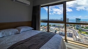 Une chambre d’hôtel avec un grand lit, une vue sur la ville et un climatiseur fixé au mur.