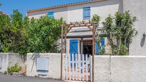 A building with a white facade, blue shutters, and a wooden pergola entrance. - La Canotière - Close to the beach (Saint-Georges-d'Oléron)