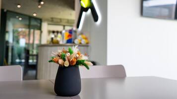 Una mesa con un jarrón de flores secas, un interior moderno con un letrero de neón y una encimera con varios objetos.
