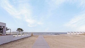 Ein Strandweg führt zu Strandhütten vor blauem Himmel.