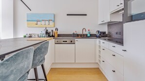 Eine moderne Küche mit weißen Schränken, einem Geschirrspüler und einer Arbeitsplatte mit diversen Geräten.