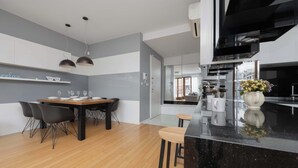 Eine moderne Küche mit schwarzem Arbeitsplatz, einem Essbereich mit Holztisch und Stühlen sowie einer sichtbaren Kücheninsel mit Hockern.