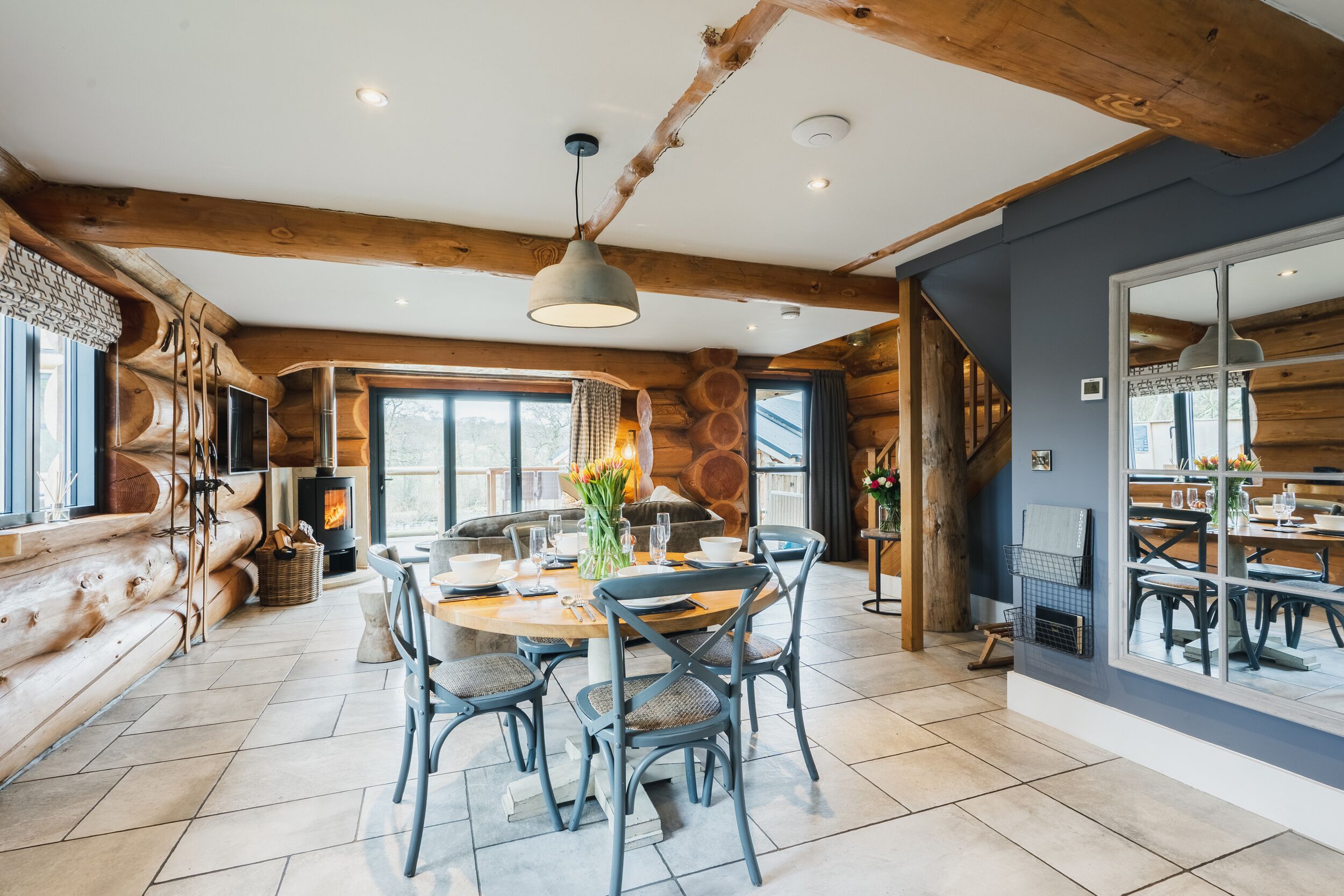 L’intérieur d’une cabane en rondins, avec un coin repas, des murs en bois et une cheminée.