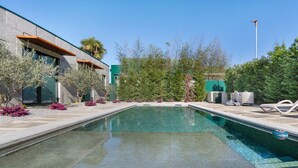 A swimming pool with a modern building, outdoor seating, and landscaping. - Apartment 'T2 Familiar Ua02' with Shared Pool, Wi-Fi and Air Conditioning (Palmeira)