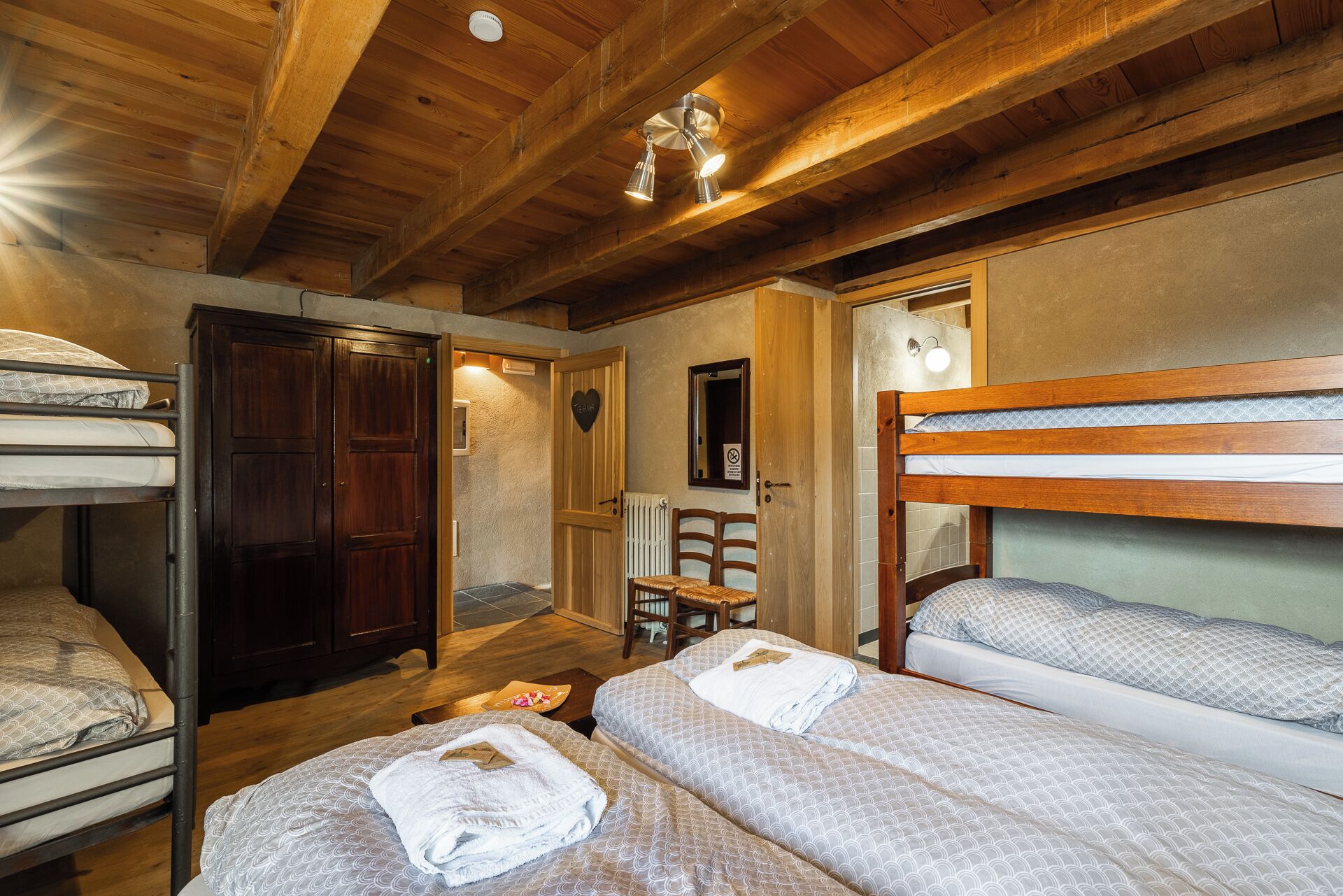 Um quarto aconchegante com beliches, vigas de madeira e uma pequena área de estar.