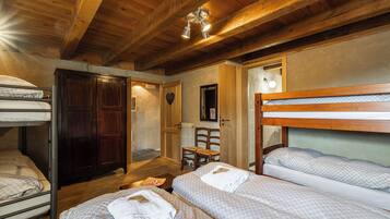 Um quarto aconchegante com beliches, vigas de madeira e uma pequena área de estar.