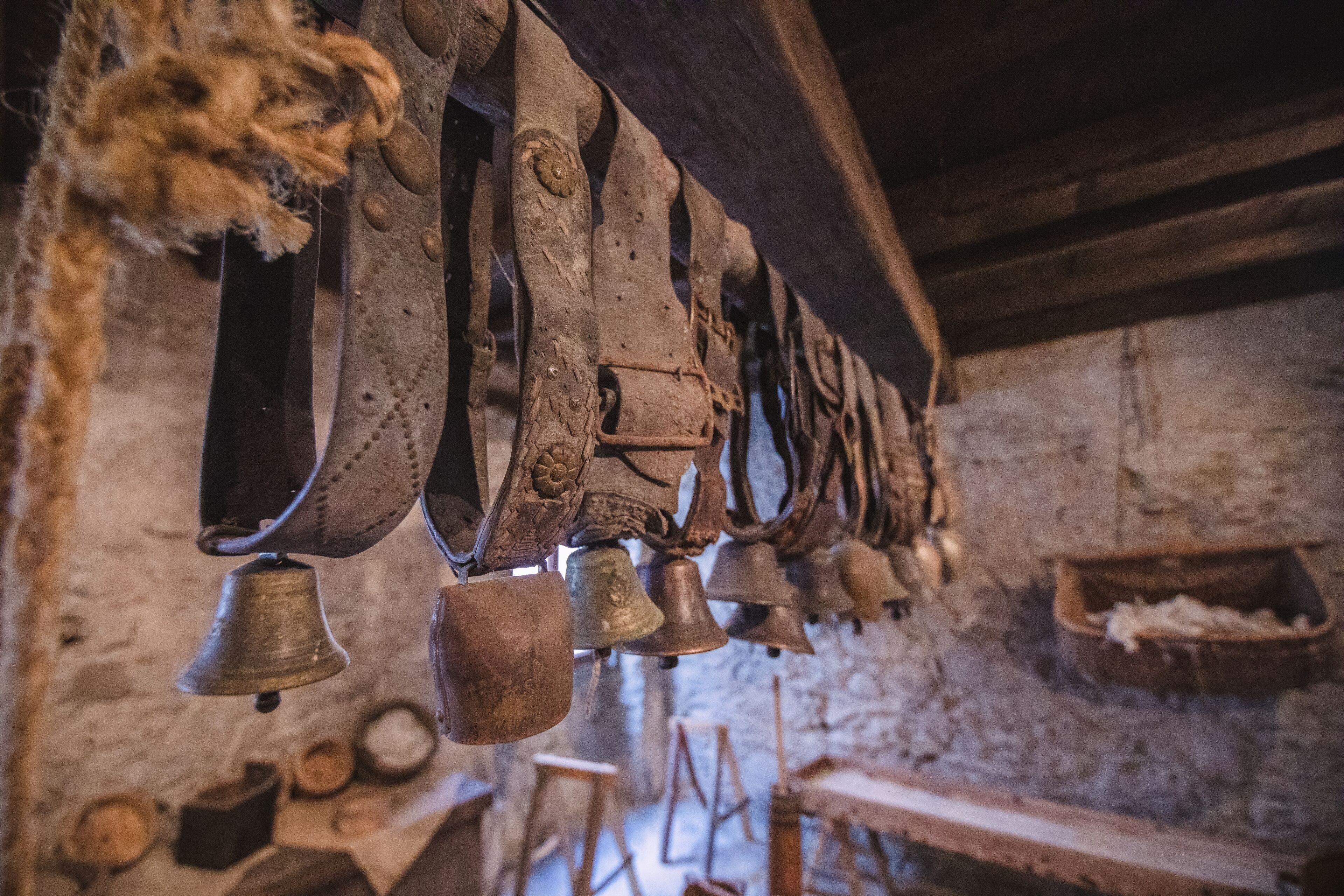 A series of bells hanging from a beam, wooden beams, and a stone wall.