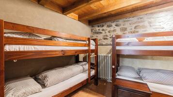 A room with two bunk beds, a stone wall, and a radiator.